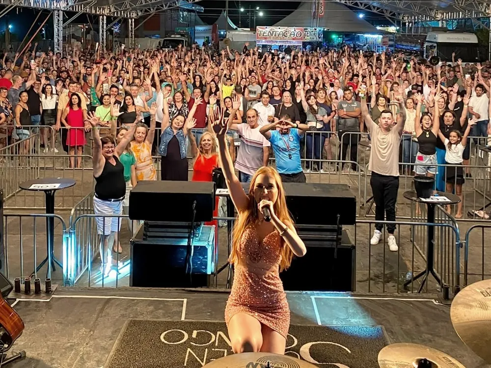 Rafaela Martins no palco, com o público lotando a tenda