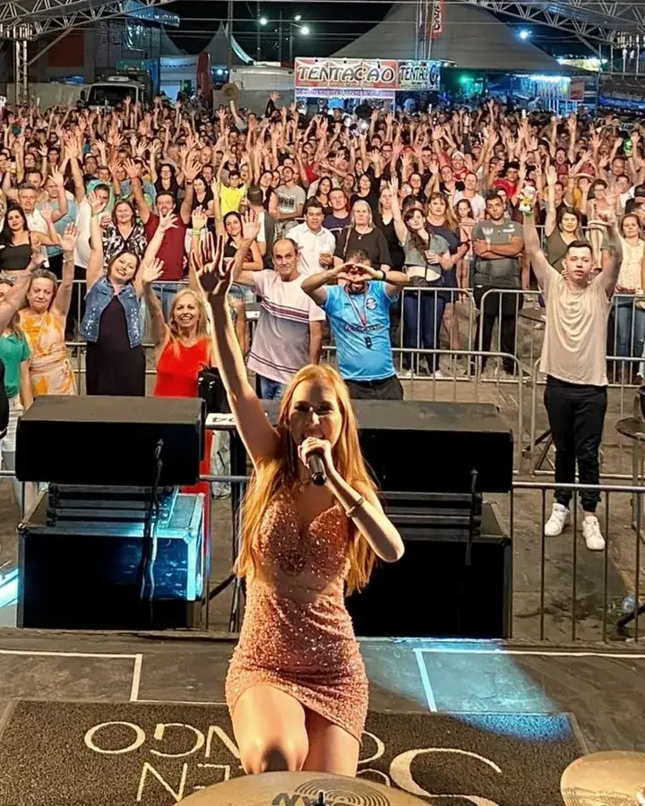Rafaela Martins no palco, com o público lotando a tenda atrás